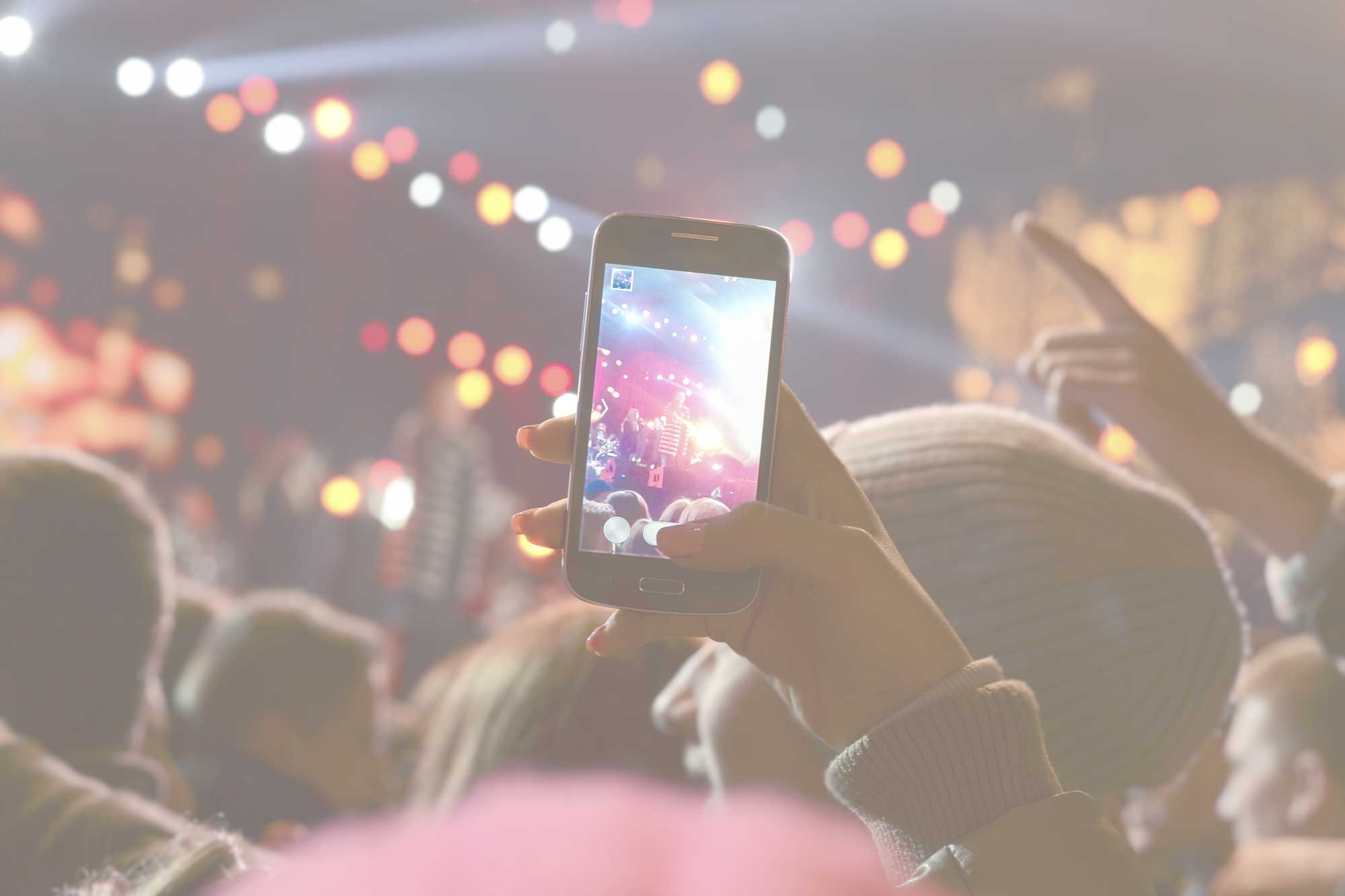 A person holding a phone at a busy concert.