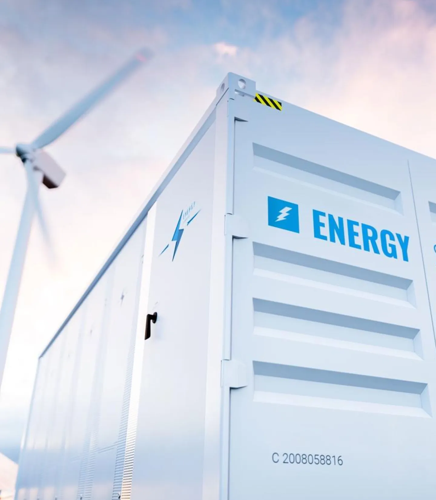 A large energy container next to a wind turbine.